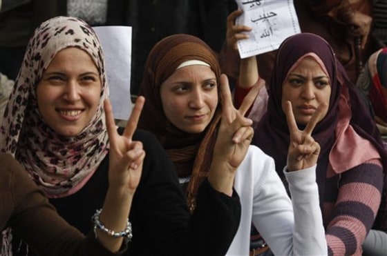 Three women gesture for victory as they attend a demonstration in Cairo, Egypt, on Sunday. Minutes before the start of a 4 p.m. curfew, at least two jets appeared and made multiple passes over downtown, including a central square where thousands of protesters were calling for the departure of President Hosni Mubarak.